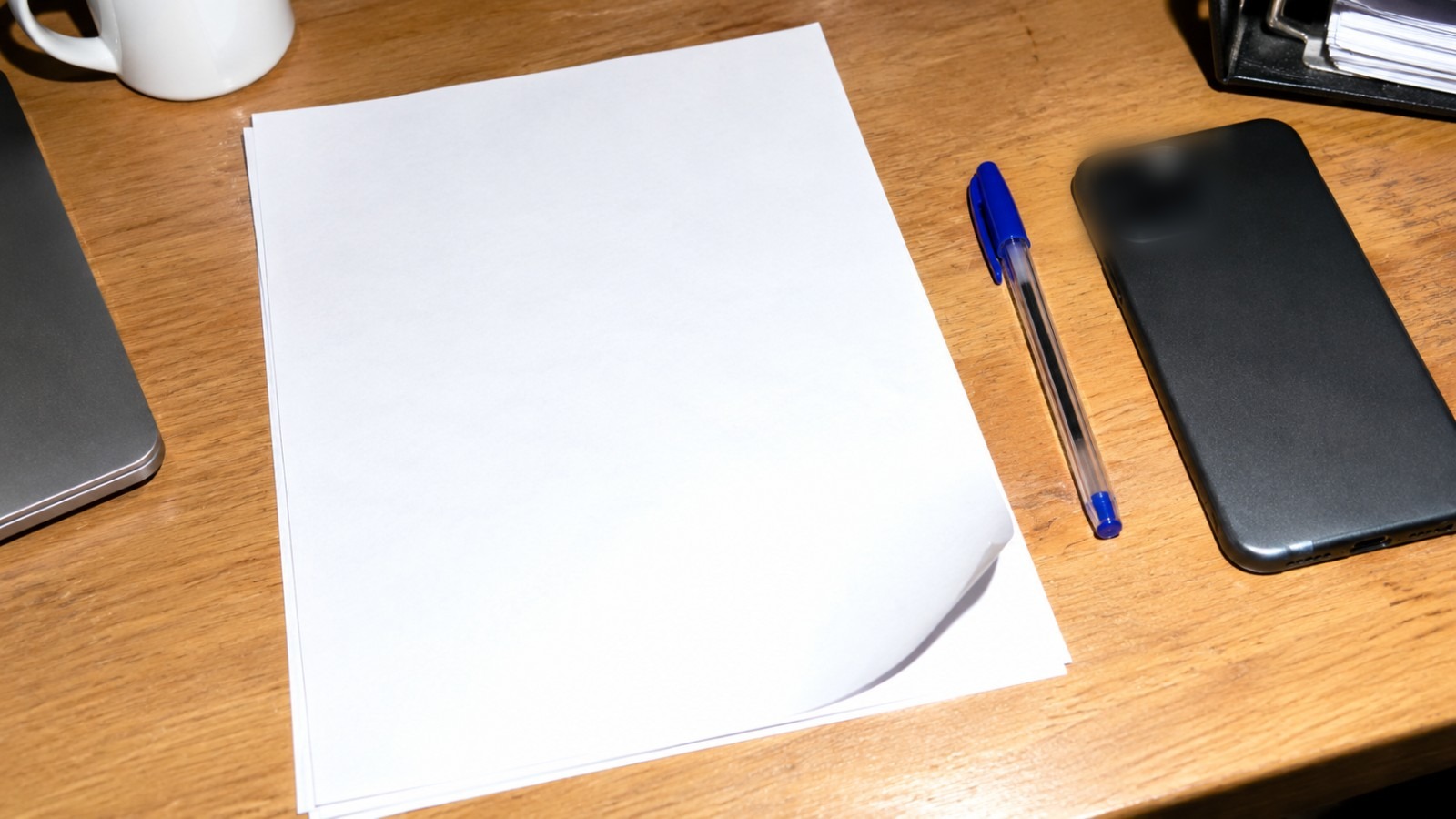 Leeres Zeichnungsformular mit Kugelschreiber und Smartphone auf einem Schreibtisch